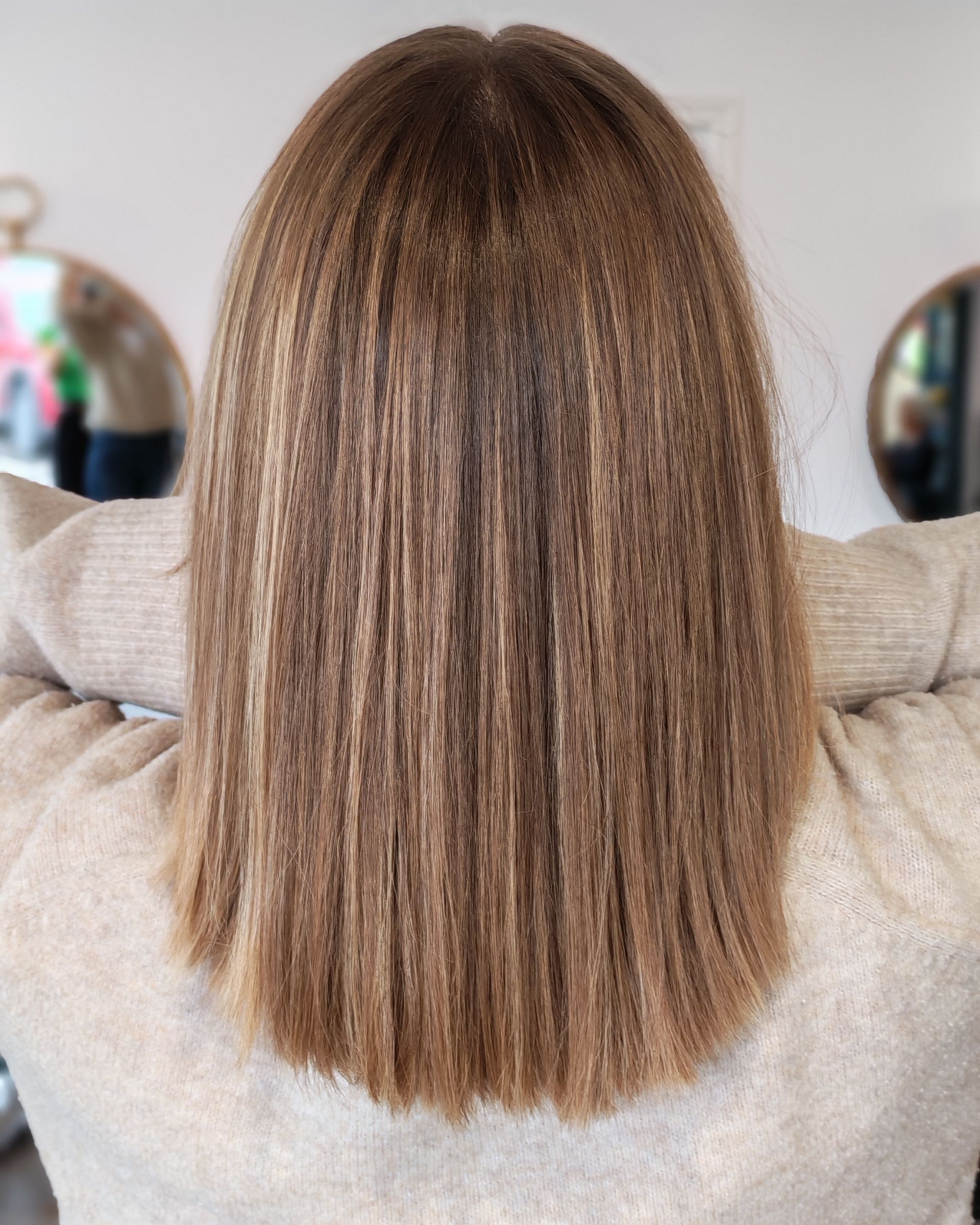 Cheveux bruns avec des reflets plus clairs, coiffés en ondulations ondulées, tombant jusqu'au milieu du dos.