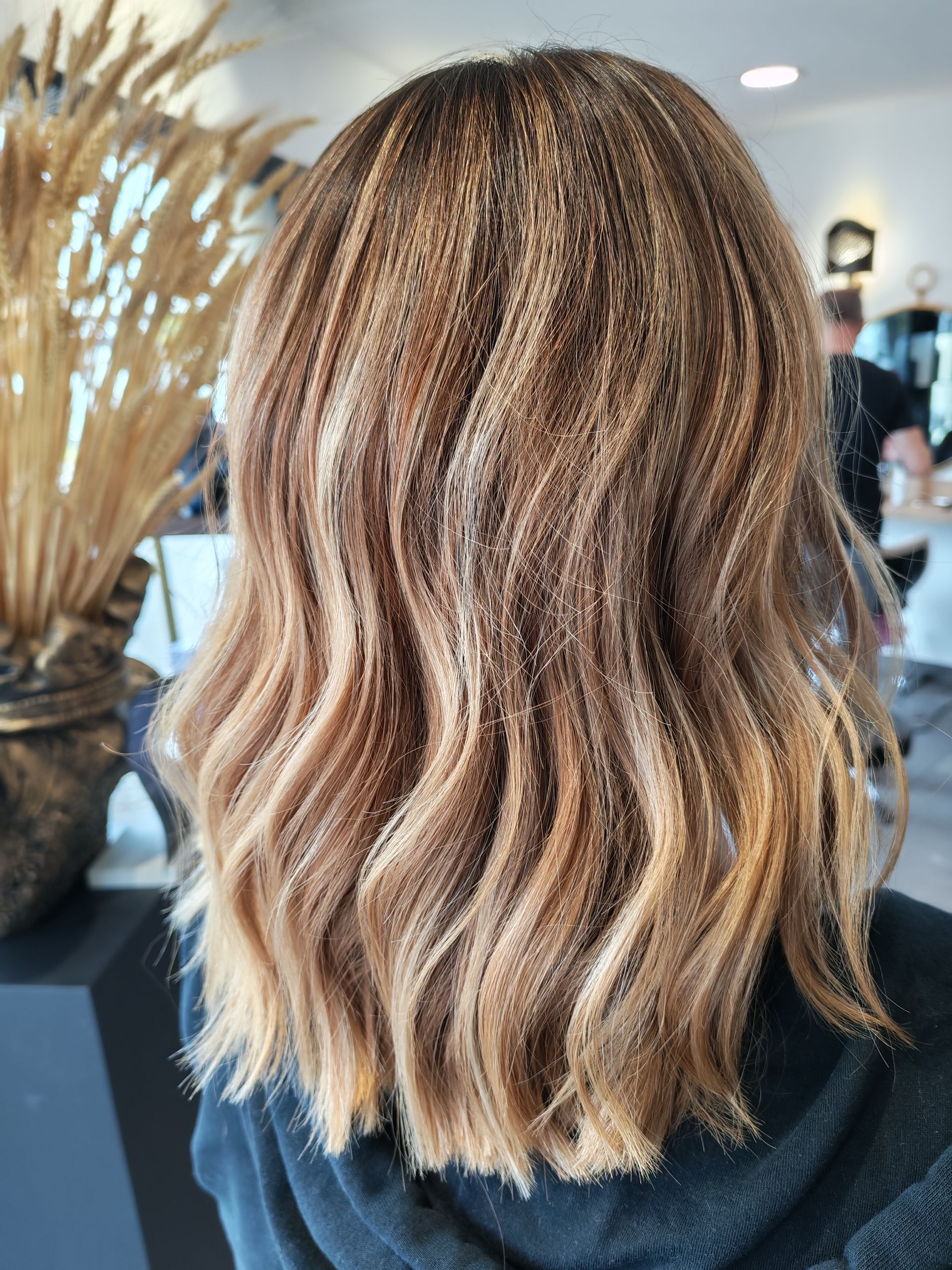 Femme aux cheveux châtain clair ondulés et crêpés ; scène en intérieur.