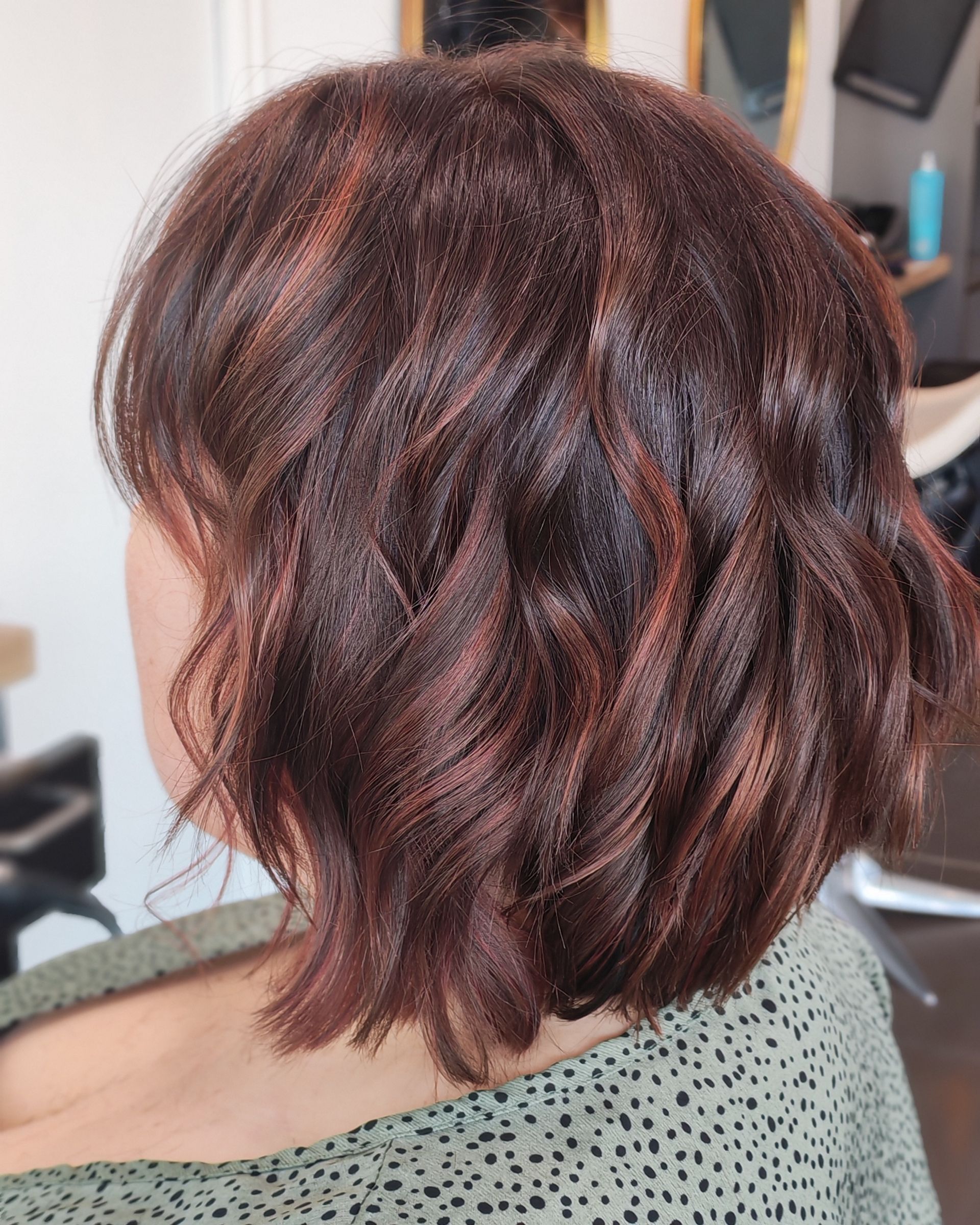 Coupe au carré ondulée brune avec des reflets auburn.