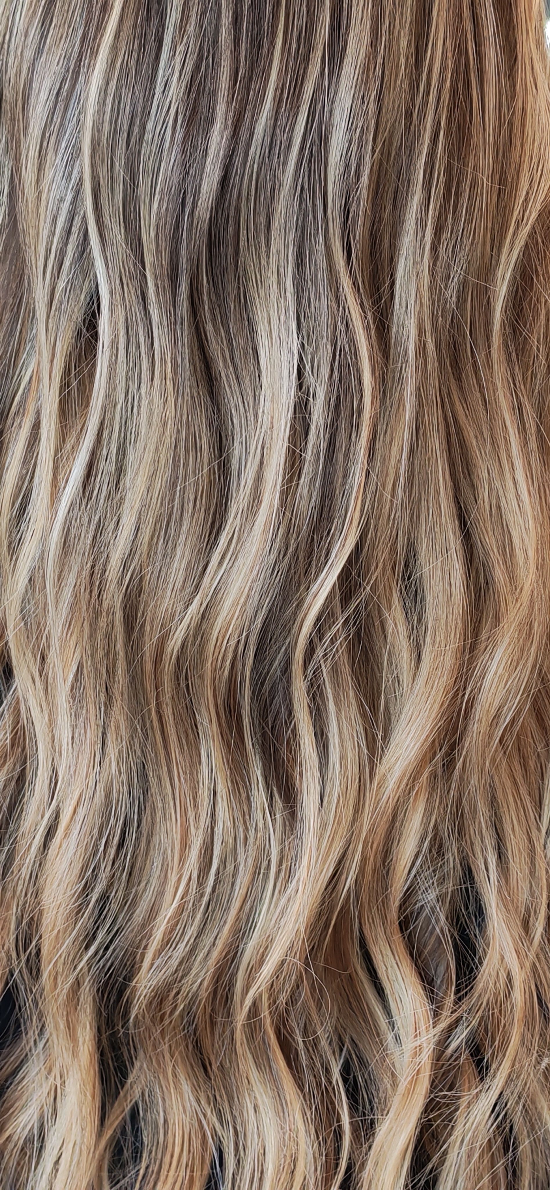 Gros plan sur des cheveux ondulés et texturés dans des tons de brun et de blond.