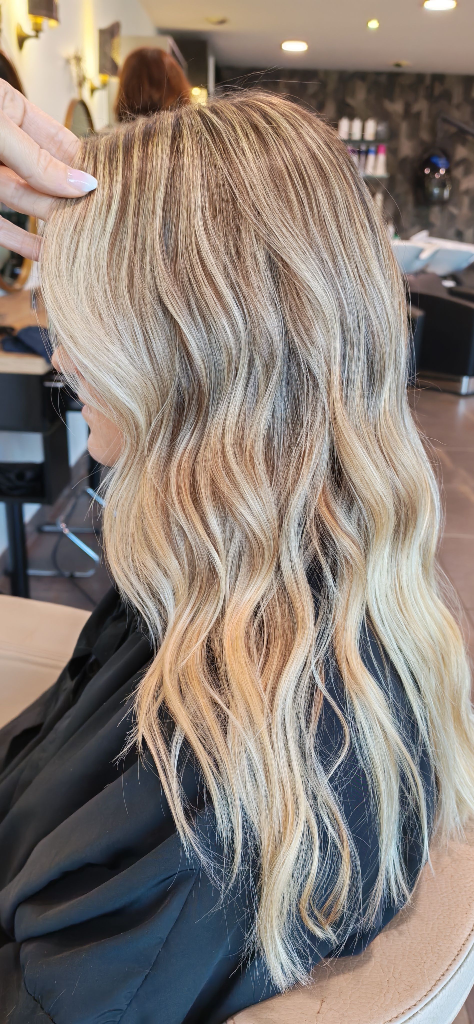 Femme aux cheveux blonds et crêpés dans un salon de coiffure.