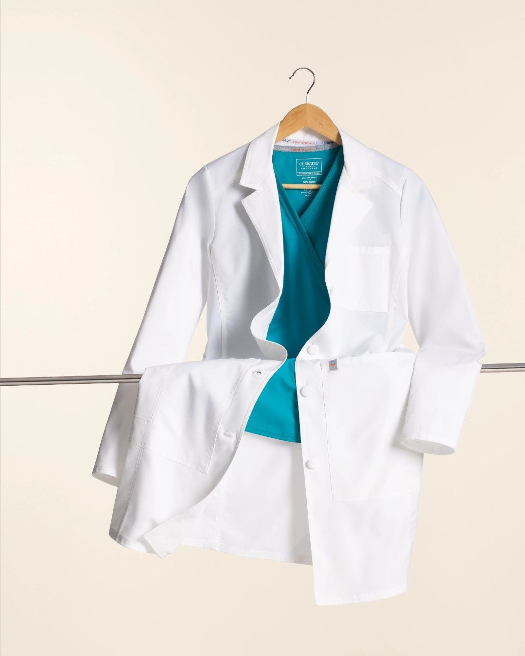 Una bata de laboratorio blanca con una bufanda azul colgando de una percha