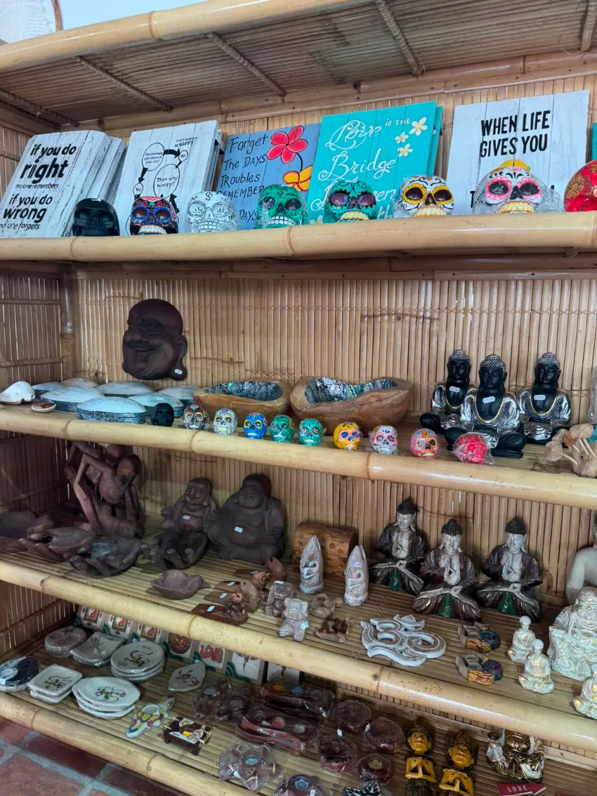 Un colorido estante de recuerdos con libros, figuritas y pequeñas artesanías en una tienda revestida de bambú.