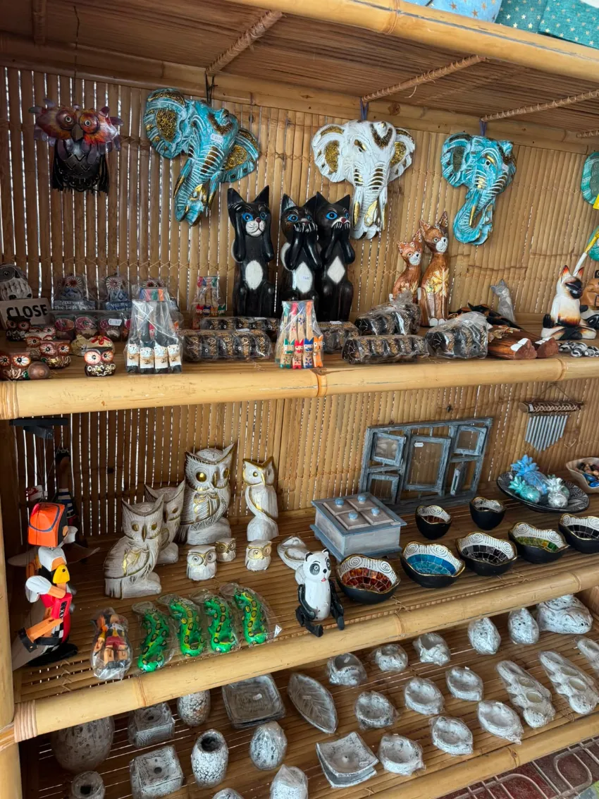 Puesto de mercado de madera que exhibe en estantes una variedad de recuerdos artesanales, figuritas y pequeñas esculturas.