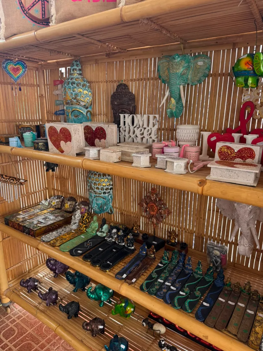 Artesanías y regalos coloridos hechos a mano expuestos en estantes de madera en un puesto de mercado de bambú.