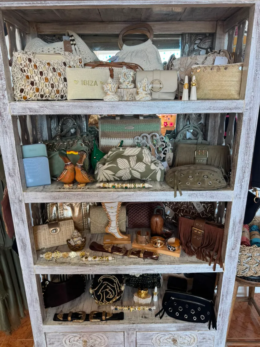 Estantería rústica de madera repleta de textiles doblados, cestas, cerámica y pequeños objetos decorativos.