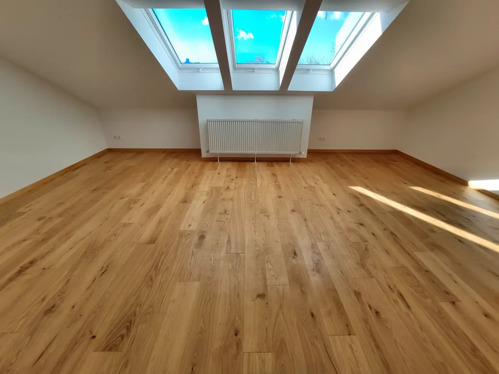 Ein leerer Raum mit Holzboden und Dachfenstern