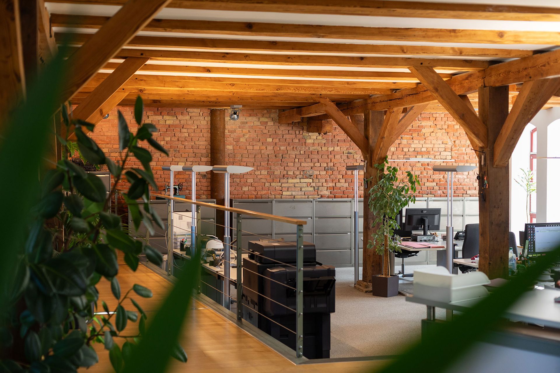 Ein großes Büro mit einer Ziegelwand und Holzbalken.