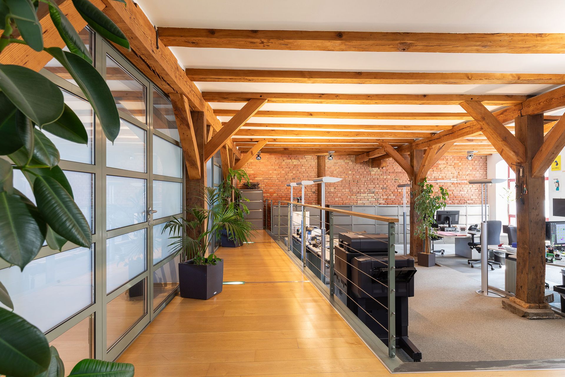 Ein langer Flur in einem Büro mit einer Ziegelwand und Holzbalken.