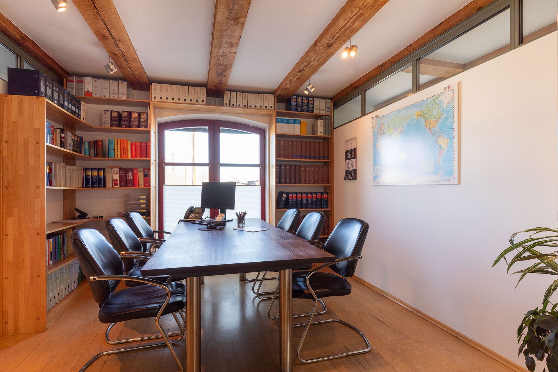 Ein Konferenzraum mit einem langen Tisch und Stühlen und einer Karte an der Wand.