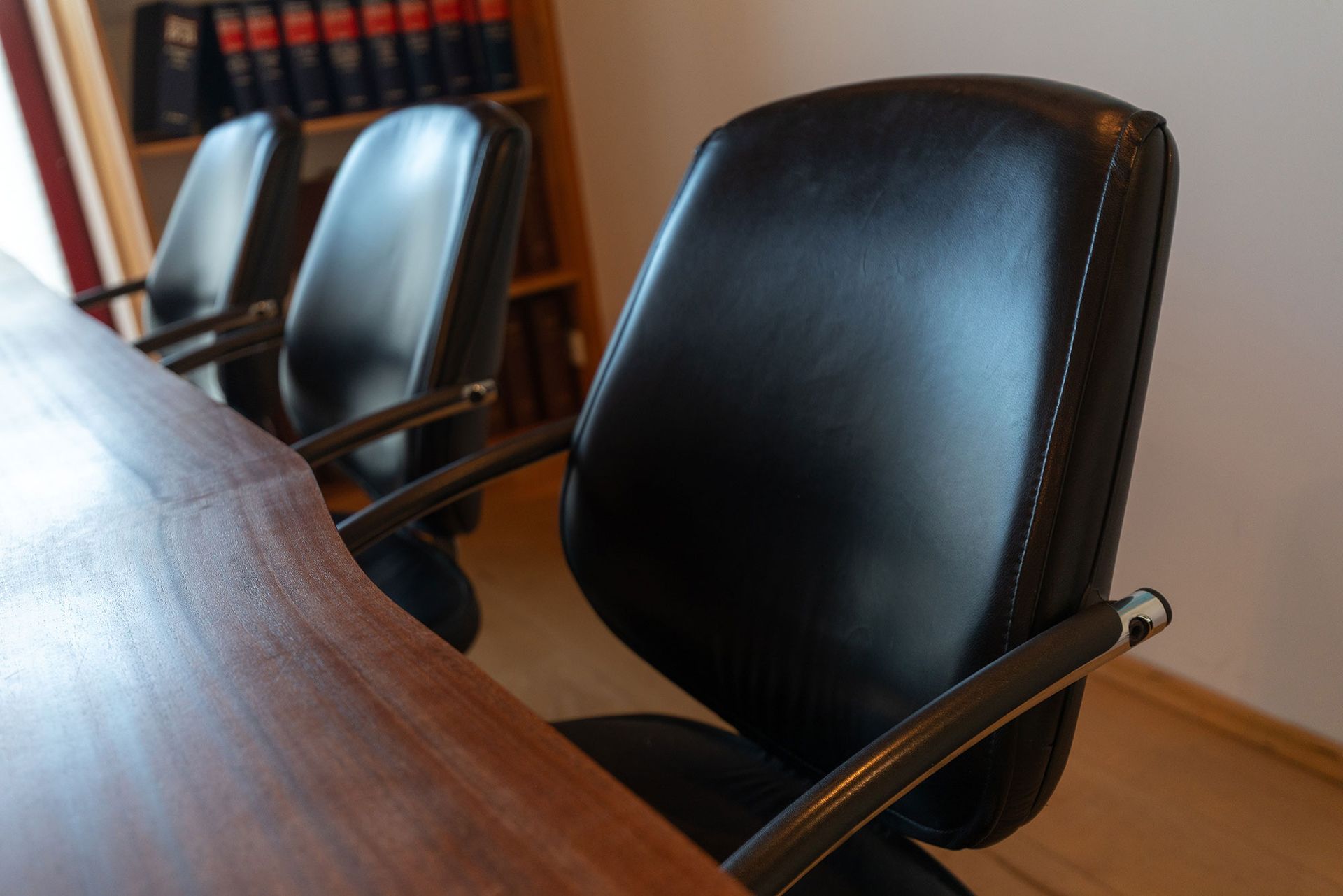 Ein schwarzer Ledersessel steht vor einem Holztisch