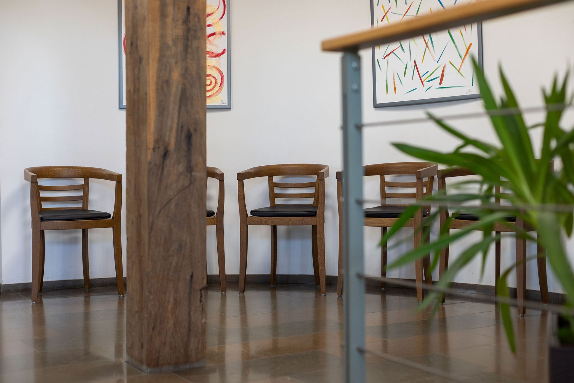 Ein Wartezimmer mit Holzstühlen und einer Pflanze