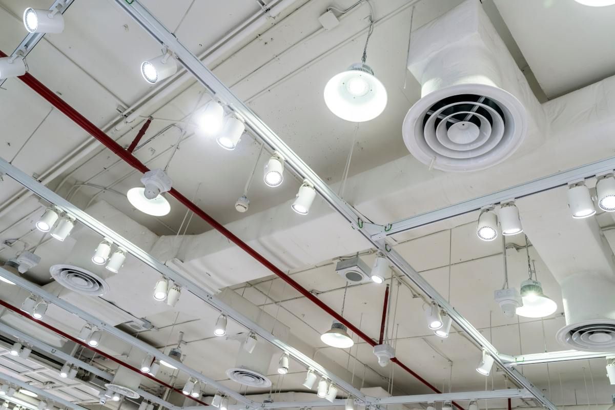 White ceiling with track lighting, vents, and red pipe.