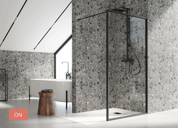 Baño moderno con cabina de ducha con marco negro sobre una pared gris texturizada, incluye bañera y taburete de madera.