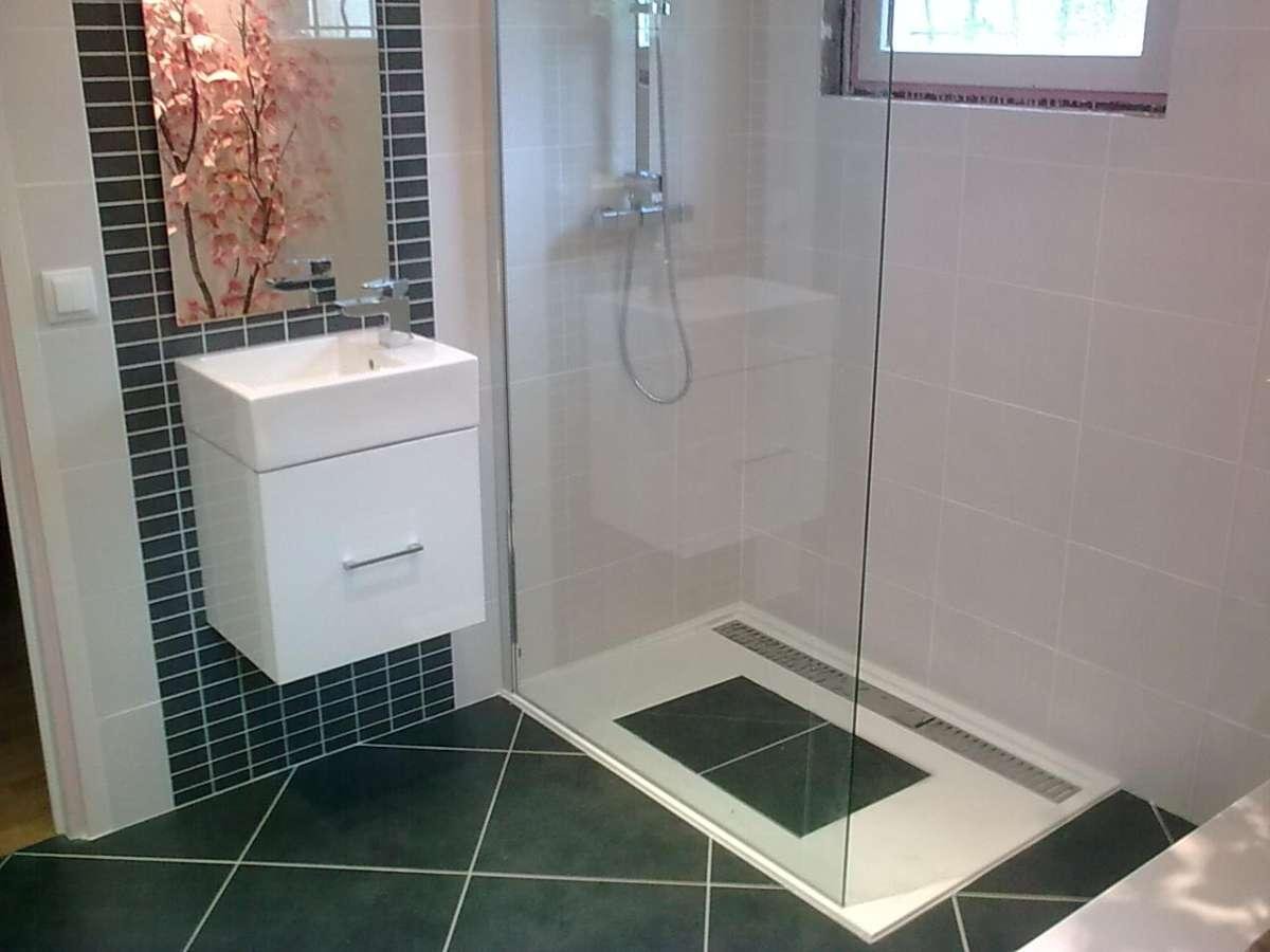 Salle de bain moderne avec douche blanche, lavabo et carrelage noir et blanc.