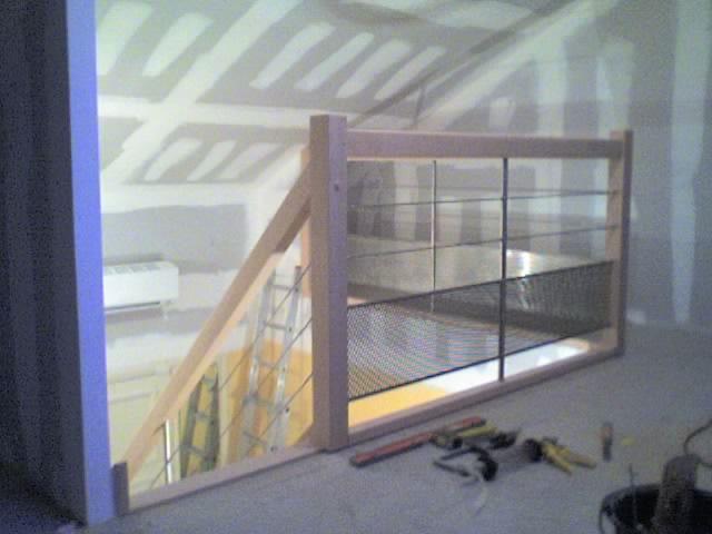 Garde-corps en bois avec barreaux horizontaux noirs, espace mezzanine intégré.