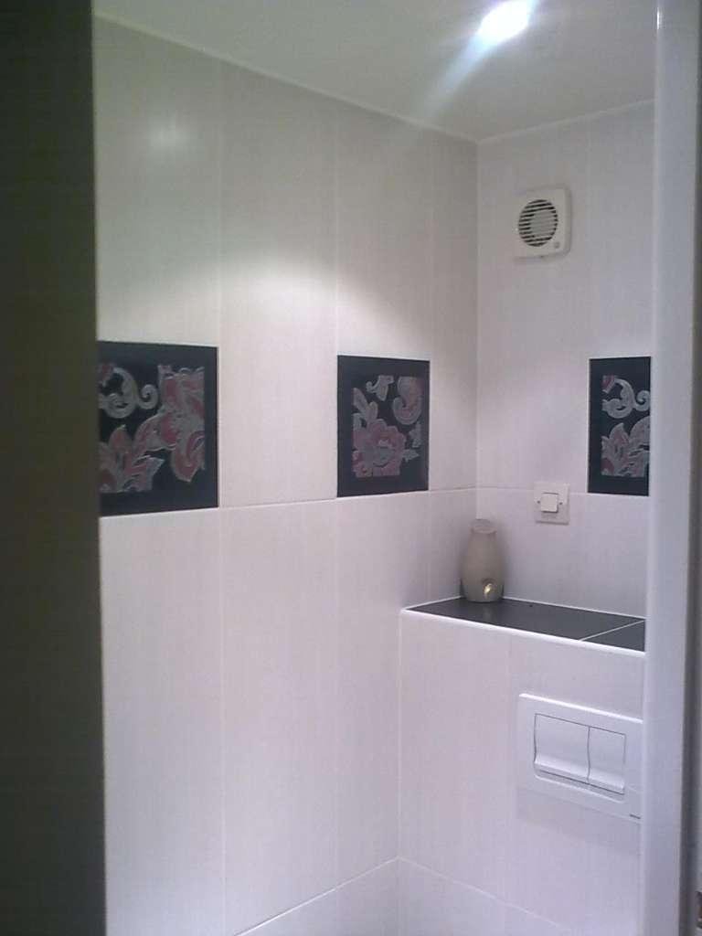 Salle de bain avec carrelage blanc, carrelage noir et ventilateur.