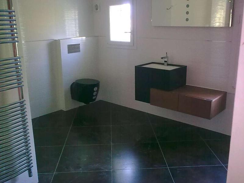 Salle de bain moderne avec carrelage noir, meuble-lavabo flottant et toilettes.