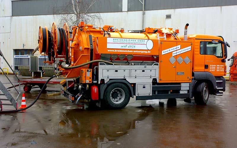 Ein großer orangefarbener Lastwagen steht vor einem Gebäude.