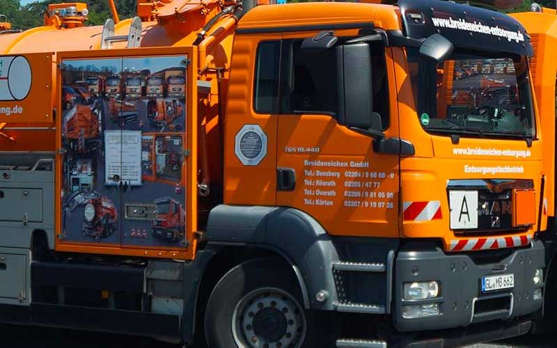 Ein orangefarbener LKW mit einem Nummernschild, auf dem steht