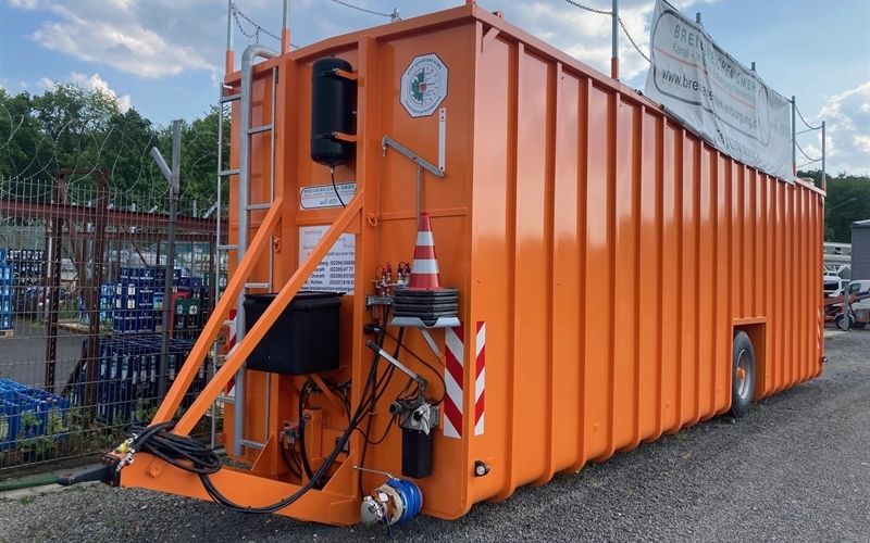 Ein großer orangefarbener Anhänger steht auf einem Parkplatz.