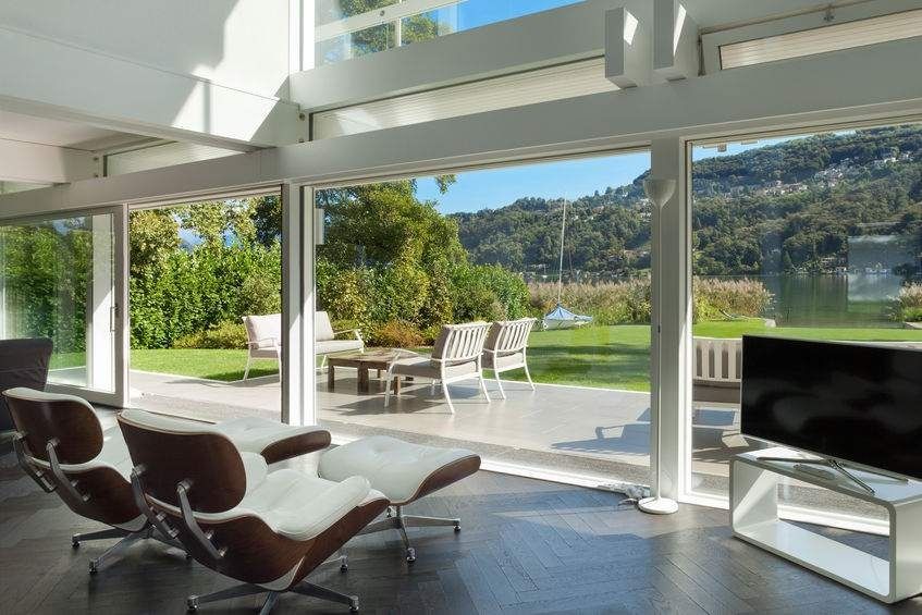 Una sala de estar con muchas ventanas y sillas y un televisor.