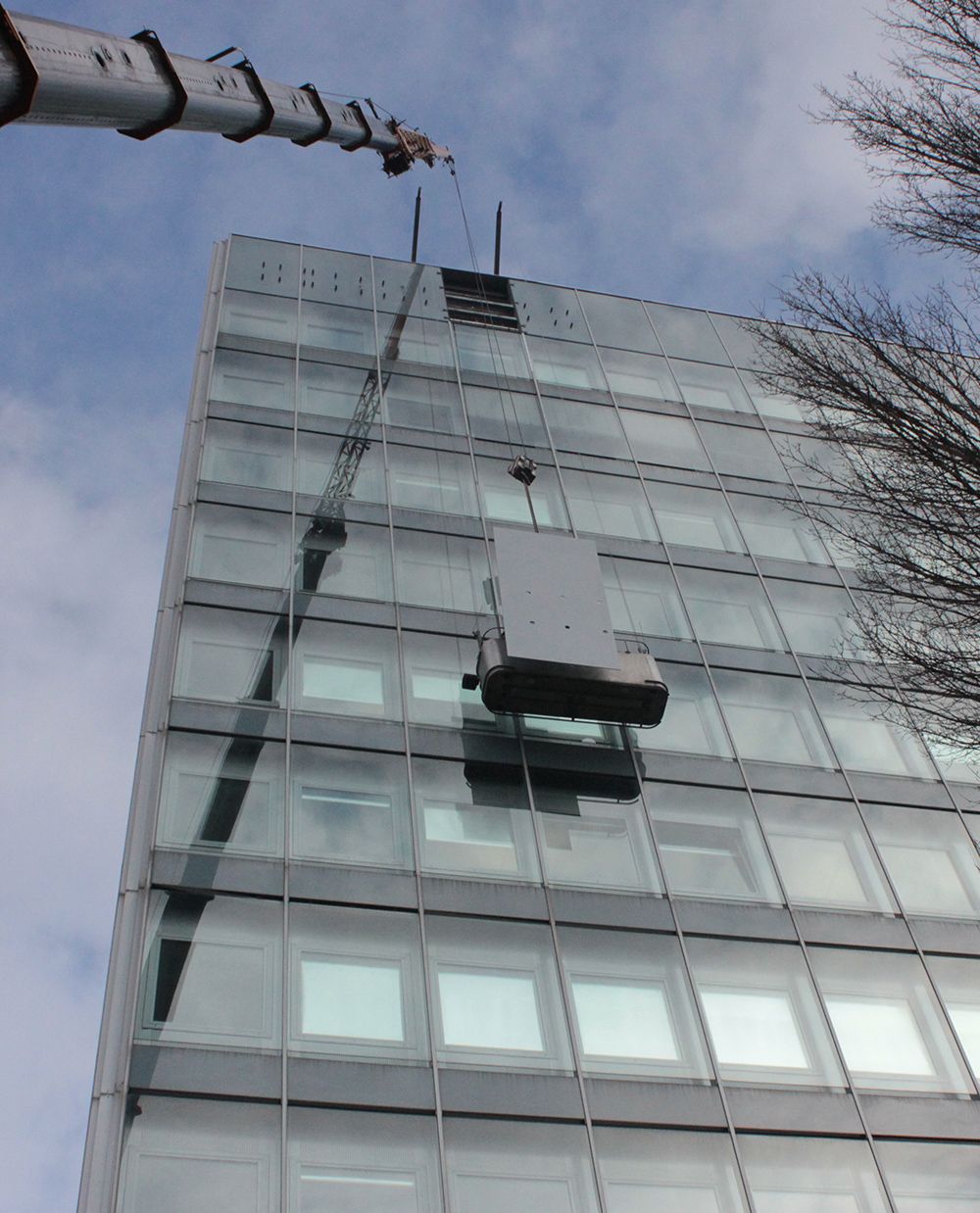 ein großes Gebäude mit vielen Fenstern wird von einem Kran gehoben