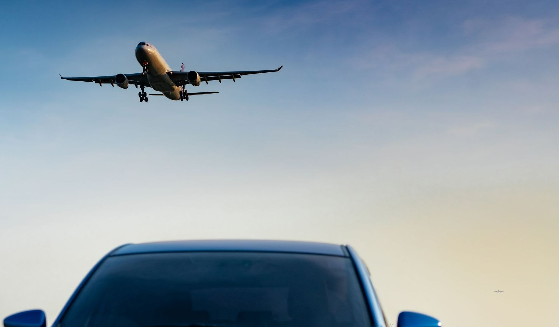 Une voiture garée avec un avion passant au-dessus