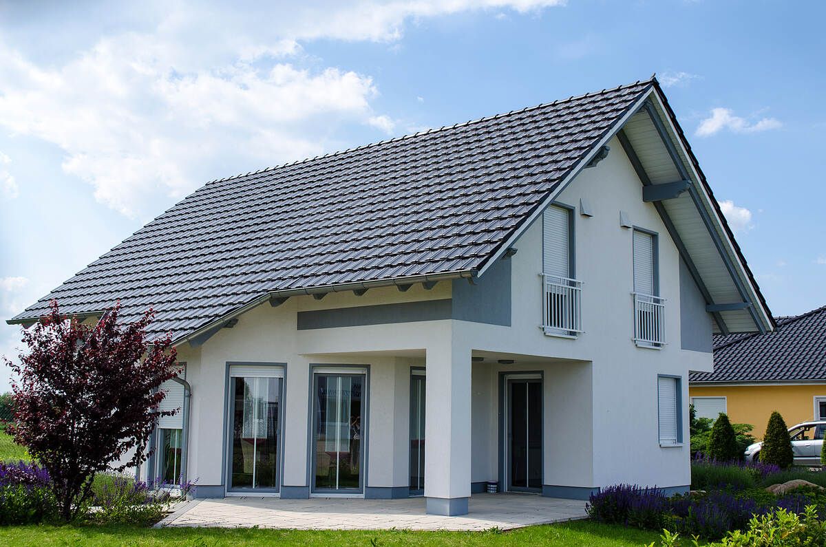 Ein weißes Haus mit grauem Dach und Glasschiebetüren