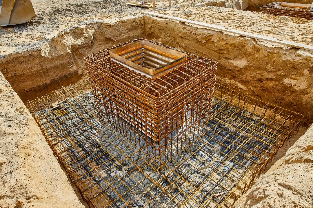 Betonfüße mit Stahlträgern stehen auf technischen Zeichnungen