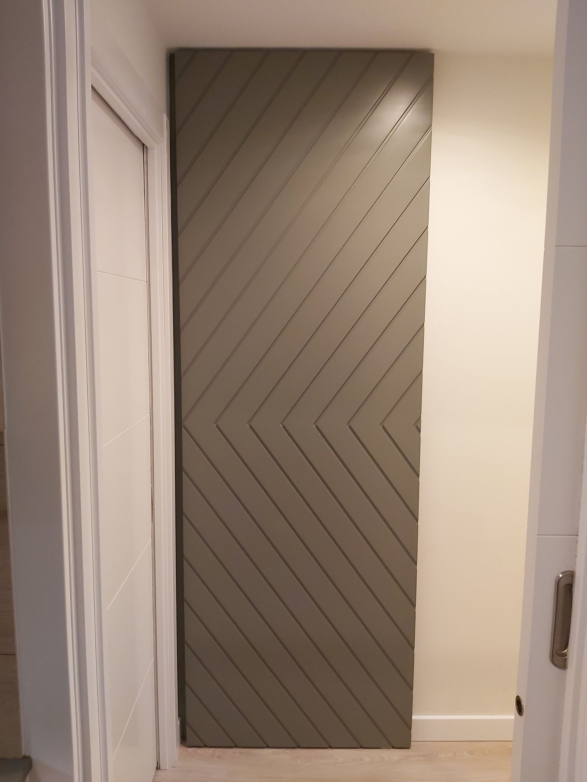 Una puerta con un patrón diagonal está en un pasillo.