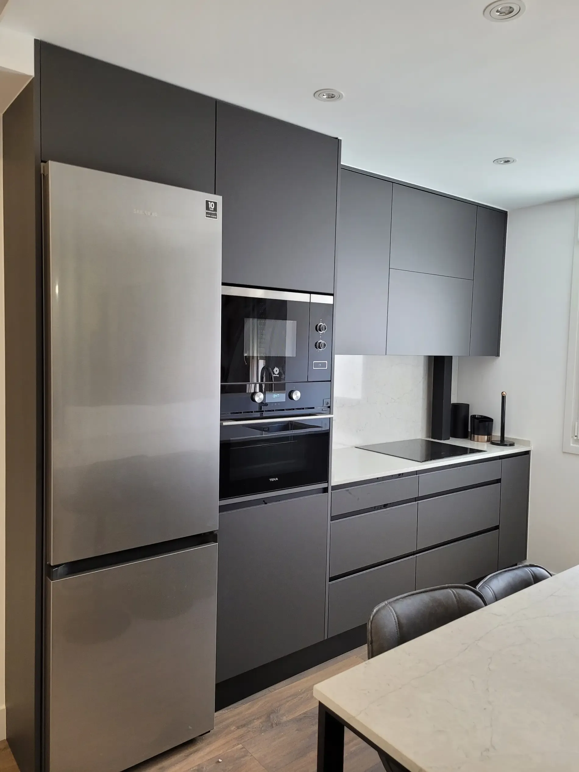 Una cocina con electrodomésticos de acero inoxidable y gabinetes negros.