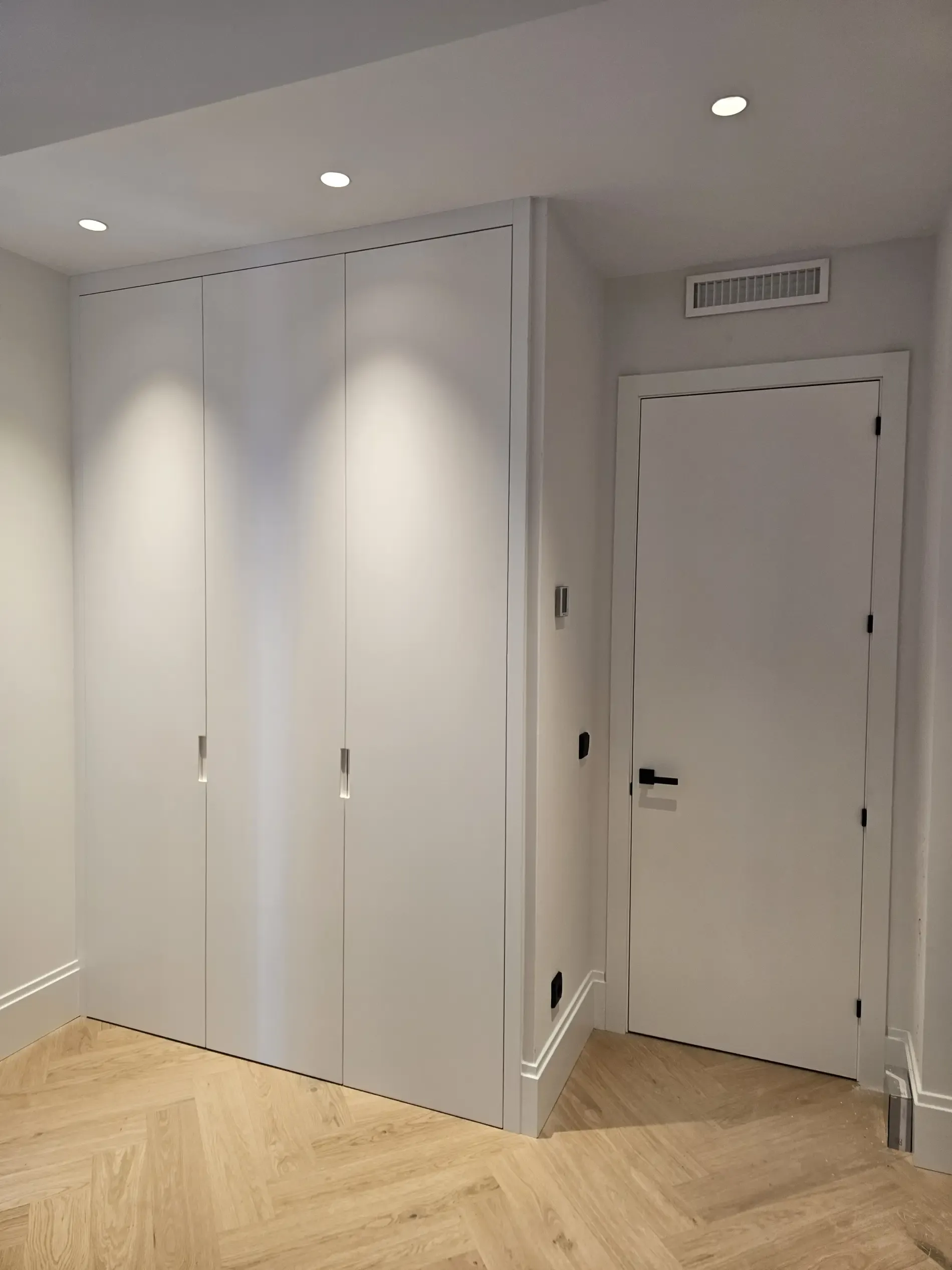 Una habitación vacía con armarios blancos y una puerta.