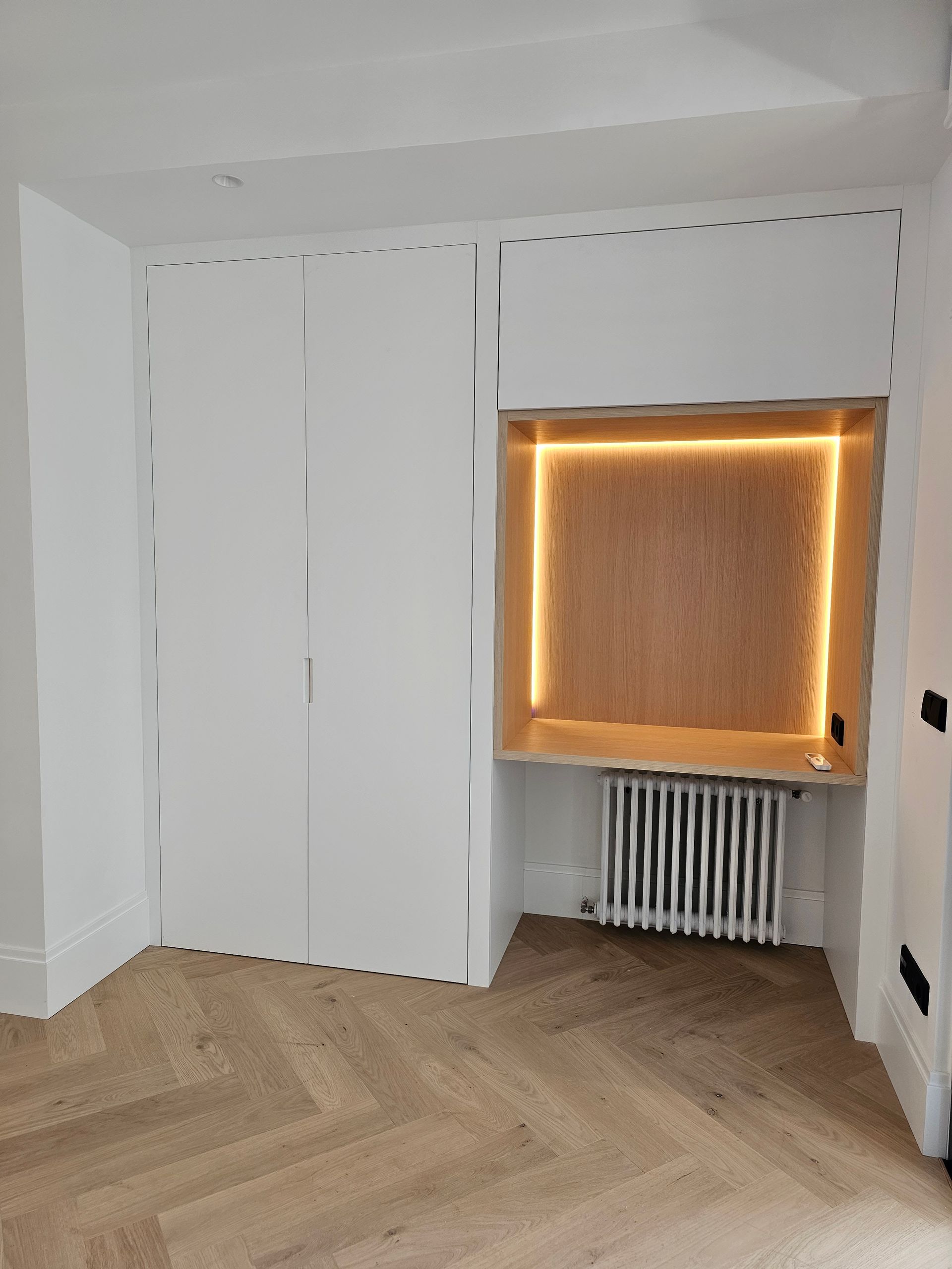 Una habitación vacía con suelo de madera y paredes blancas.