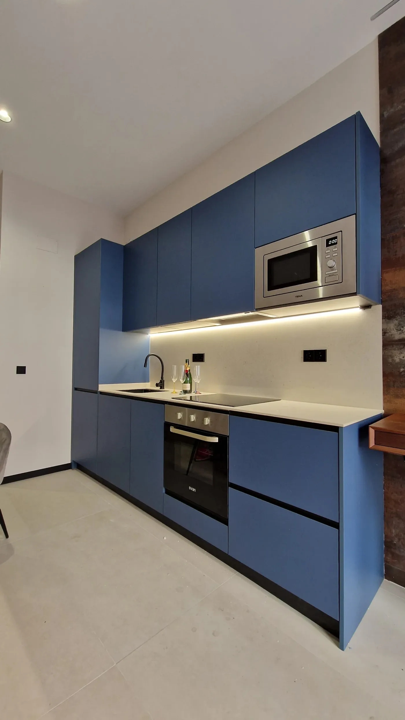 Una cocina con gabinetes azules y electrodomésticos de acero inoxidable.