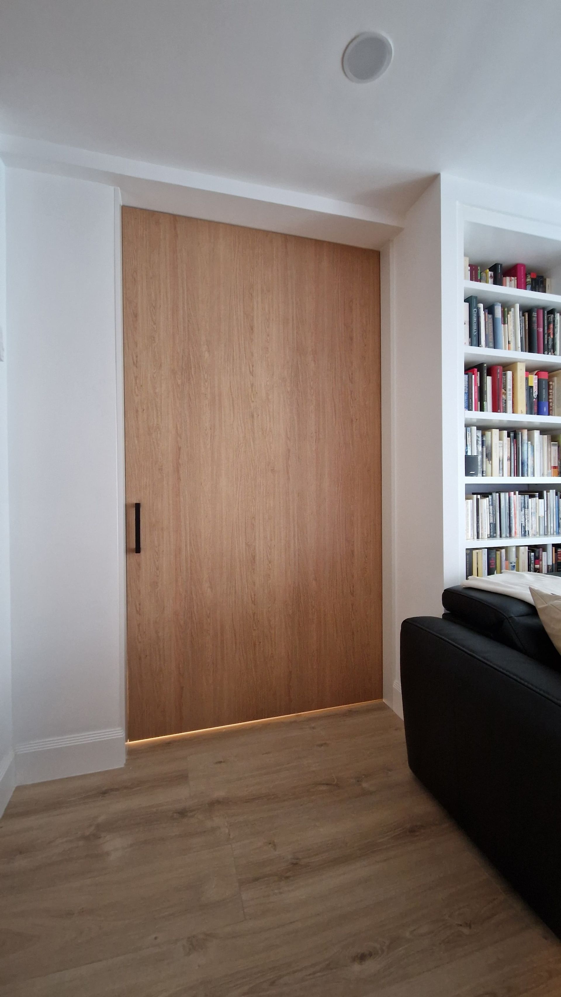 Una sala de estar con una gran puerta de madera y un sofá negro.