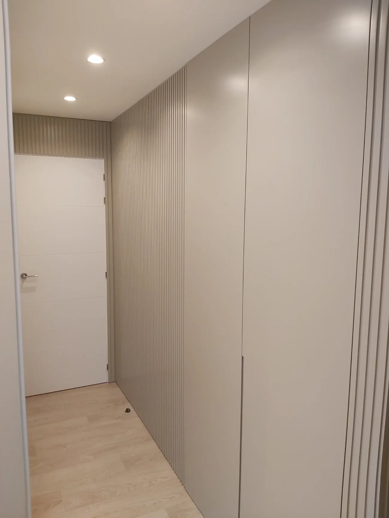 Un pasillo con paredes blancas y una puerta blanca.