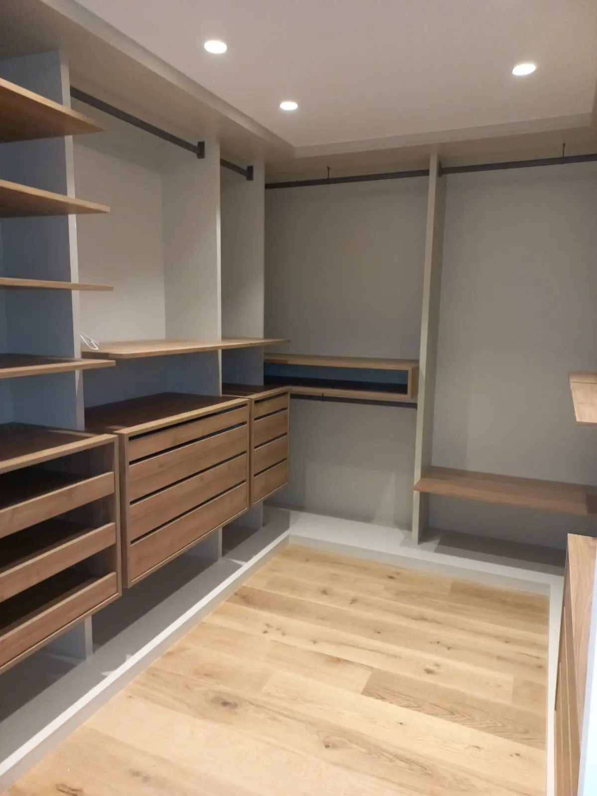 Un vestidor con estantes y cajones de madera.