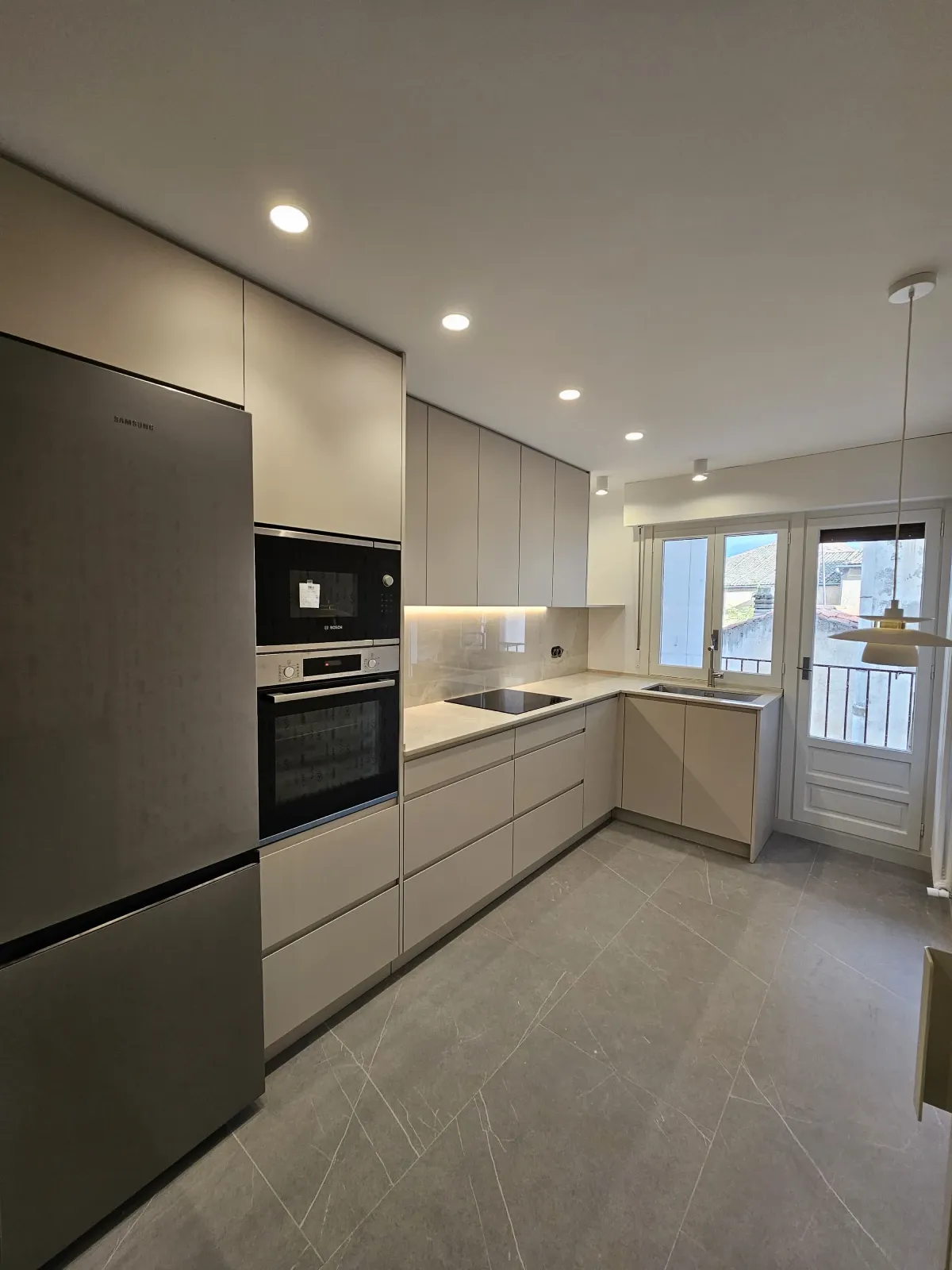 Una cocina con frigorífico, horno, microondas y fregadero.