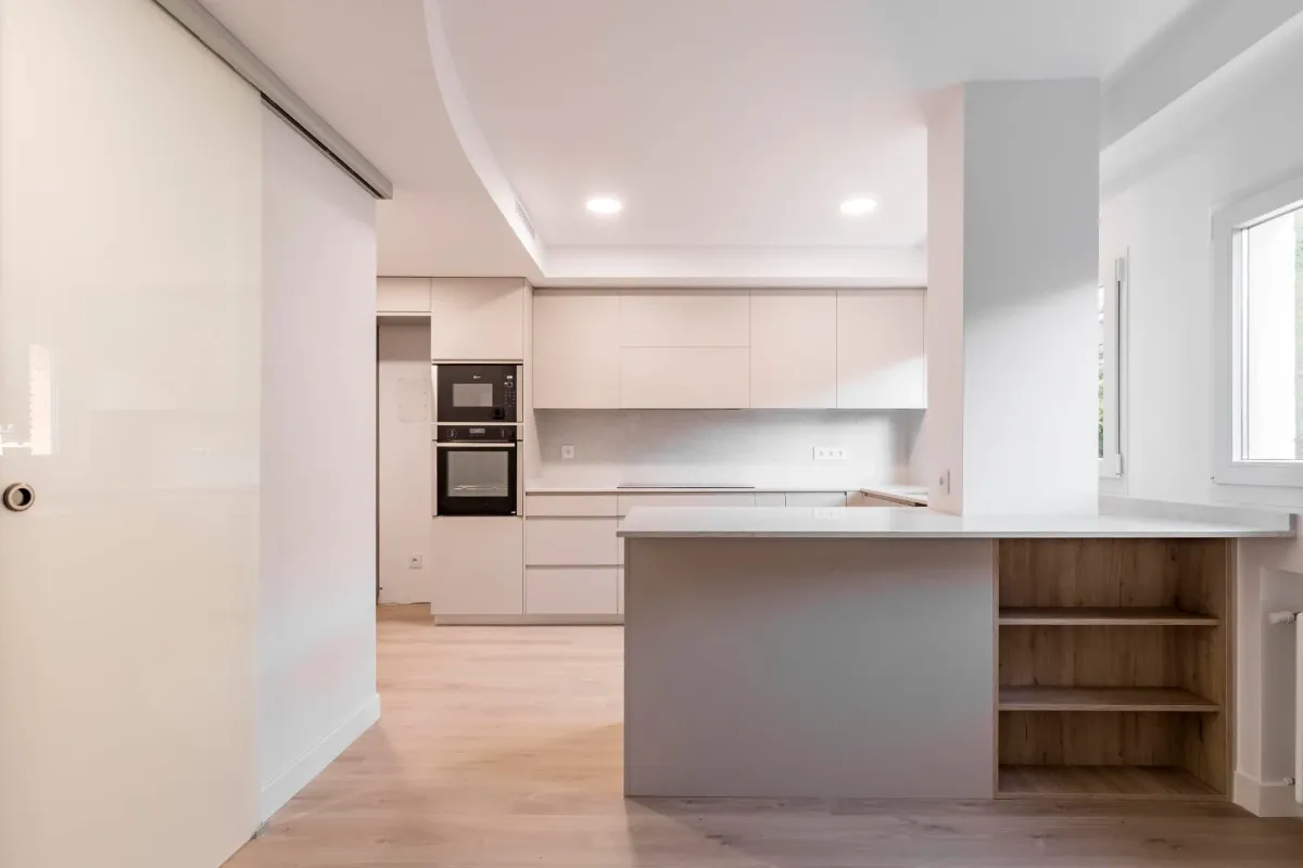 Una cocina con gabinetes blancos y una gran isla en el medio.