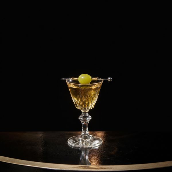 A clear martini in a stemmed glass garnished with a single castelvetrano olive