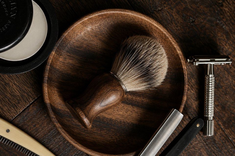 Shaving brush, bowl and razor on dark wood