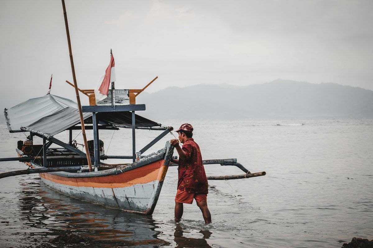 A fisherman pushing an outrigger into the shallows