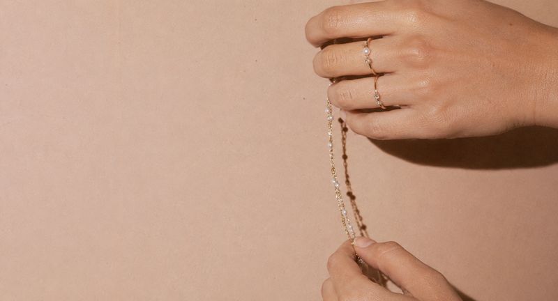Hands wearing Stack rings and a gold chain