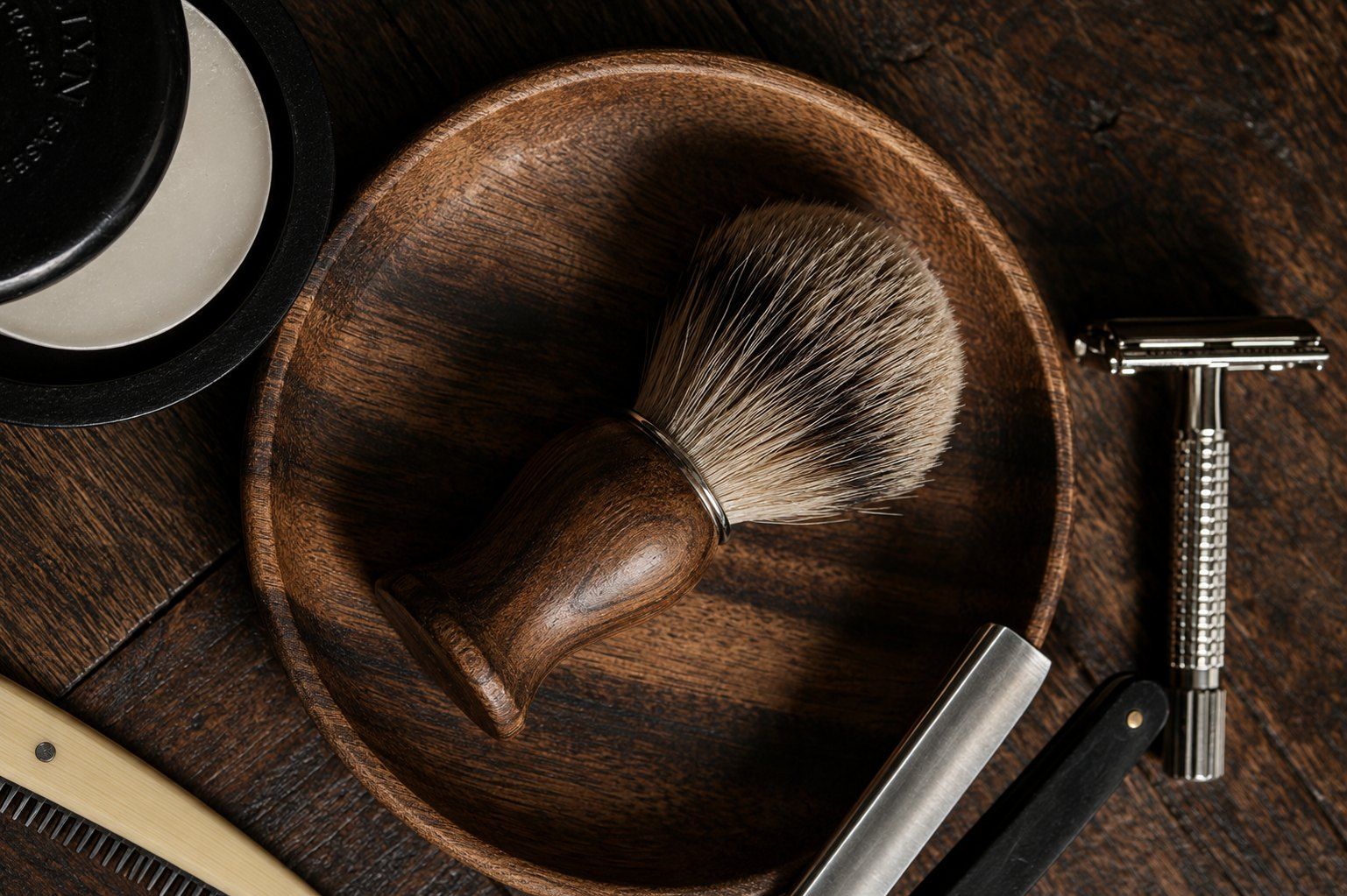 Shaving brush, bowl and razor on dark wood